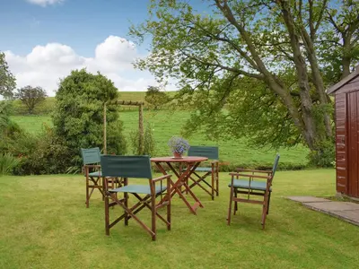 a wooden table and chairs in the grass at Gean Cottage in Powmill