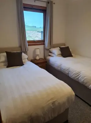 two beds in a room with a window at Kings Reach - Dunadd Cottage in Lochgilphead