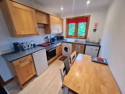 a kitchen with a wooden table and a counter top at Kings Reach - Dunadd Cottage in Lochgilphead