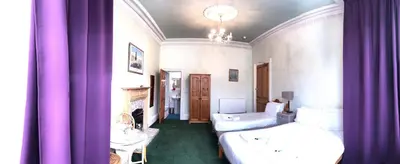 a bedroom with purple curtains and a bed and a sink at Cruachan Guest House in Edinburgh