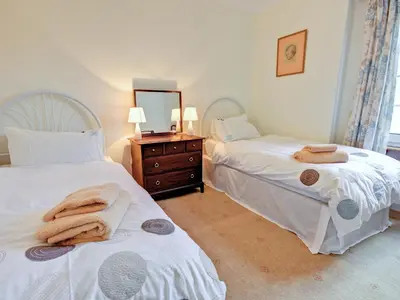 a bedroom with two beds and a dresser and a mirror at The Cottage in Girvan