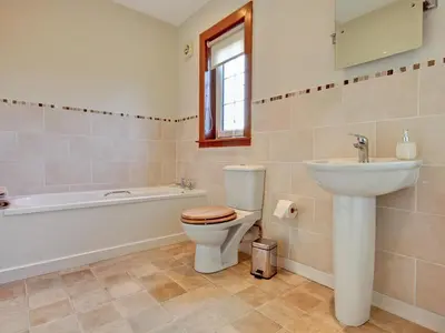 a bathroom with a toilet and a sink and a bath tub at The Cottage in Girvan