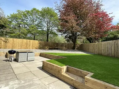 a backyard with a lawn and a fence with a grill at Lochindaal - Beautiful, Spacious 4 Bedroom House in Kintyre in Whitehouse