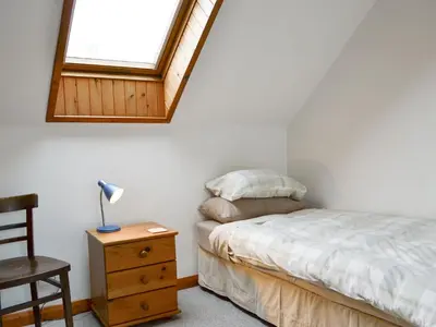 a bedroom with a bed and a desk and a window at Blairhosh Cottage in Balloch