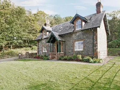 an old stone house with a grass yard at Gardener's Cottage-Uxt in Corsock