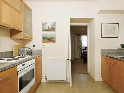a kitchen with wooden cabinets and a stove top oven at Gardener's Cottage-Uxt in Corsock