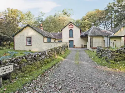 an old house with a stone wall next to a street at Stables Cottage-Uud in Corsock