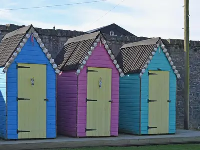 four colourful beach huts lined up against a wall at Marwhin Cottage - Swws in Kirkpatrick Durham