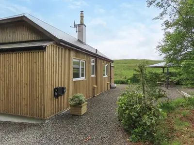 a wooden cabin with a gravel driveway next to it at Swallow Lodge in Carsphairn