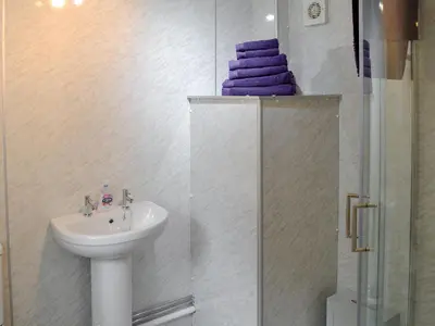 a bathroom with a sink and a shower with purple towels at Barnhill Bothy in Moffat