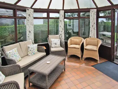 a conservatory with a couch and chairs and a table at Dunmaghlas in Pirnmill