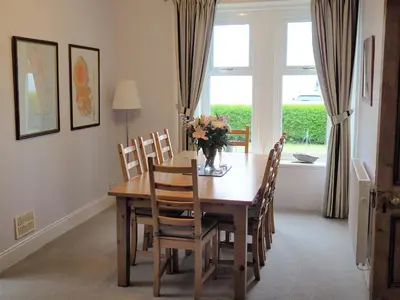 a dining room table with chairs and a vase of flowers on it at Dunmaghlas in Pirnmill