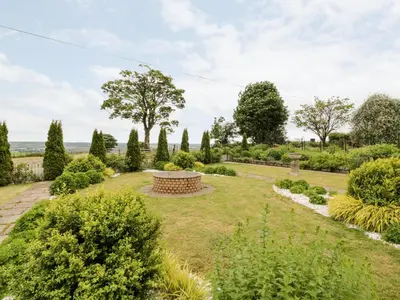 a garden with a bench in the middle at Braeface Cottage in Bonnybridge