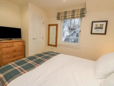 a bedroom with a bed and a tv and a window at Taigh Geal in Killin