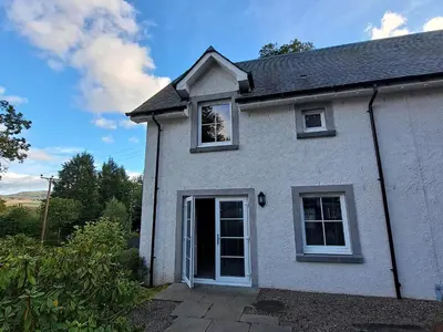 a white house with a door and windows at Taigh Geal in Killin