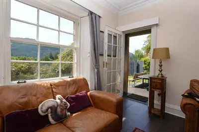a brown leather couch in a living room with a window at Eckford House in Dunoon