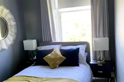 a bedroom with a bed with blue walls and a window at Stunning 3 bedroom Victorian home near Pollok country park in Glasgow