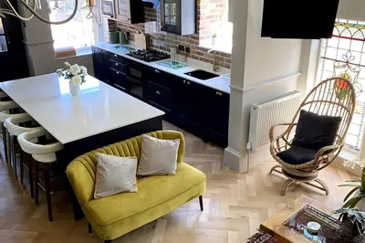 a kitchen with a yellow couch and a kitchen island at Stunning 3 bedroom Victorian home near Pollok country park in Glasgow