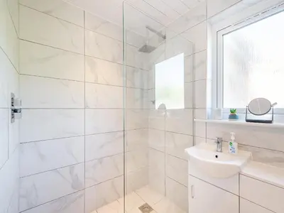 a white bathroom with a shower and a sink at Seamill Cottage in Seamill