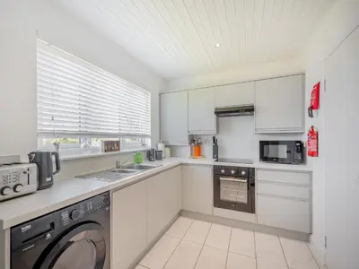 a kitchen with white cabinets and a washer at Seamill Cottage in Seamill