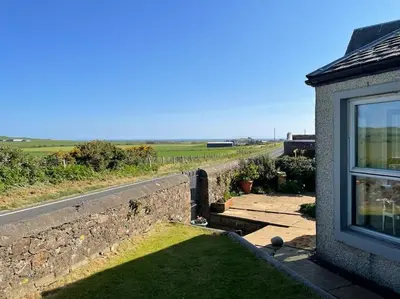 a house with a stone wall and a yard with a window at Southend, Mull of Kintyre, Campbeltown in Campbeltown