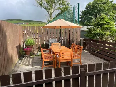 a table and chairs with an umbrella on a patio at Southend, Mull of Kintyre, Campbeltown in Campbeltown