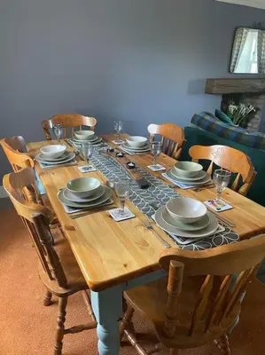 a wooden table with chairs and plates and wine glasses at Southend, Mull of Kintyre, Campbeltown in Campbeltown