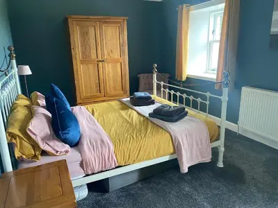 a bedroom with a bed with yellow sheets and blue walls at Southend, Mull of Kintyre, Campbeltown in Campbeltown