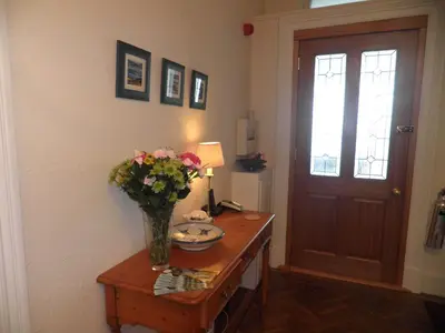 a vase of flowers on a table next to a door at Douglas Park Guest House in Dunoon