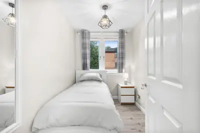 a bed in a white room with a window at The Riverside Rest 1 in Stirling