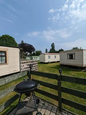a bbq grill on a wooden table next to a fence at 30 Glenfinart Caravan Park in Dunoon