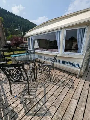 a patio with a table and chairs on a deck at 30 Glenfinart Caravan Park in Dunoon