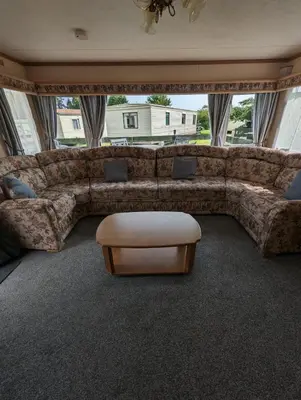 a living room with a large couch and a table at 30 Glenfinart Caravan Park in Dunoon