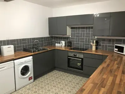 a kitchen with gray cabinets and a washer and dryer at The Villas in Helensburgh