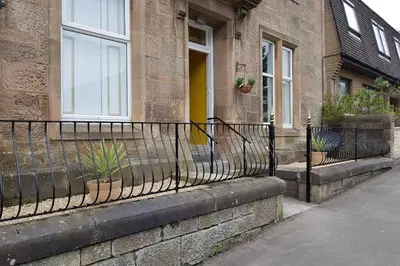 a wrought iron fence in front of a building at Snug - Fountain Bank Apartment in Helensburgh