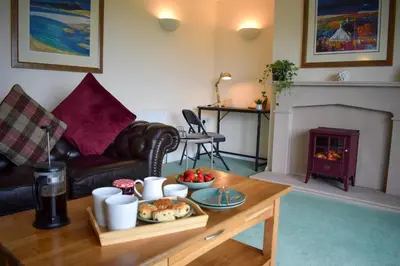 a living room with a coffee table and a fireplace at Heatherbank Cottage in Onich