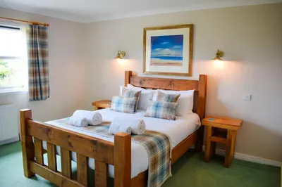 a bedroom with a large bed with towels on it at Heatherbank Cottage in Onich