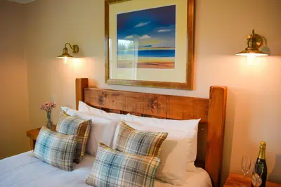 a bedroom with a bed with pillows and a picture on the wall at Heatherbank Cottage in Onich
