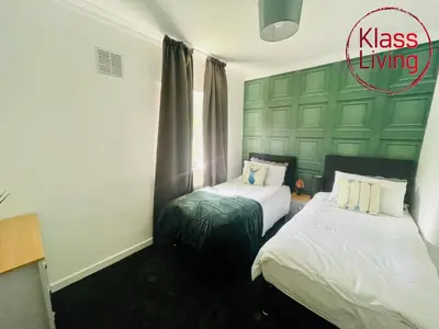 a bedroom with two beds and a green wall at Mitchell Apartment by Klass Living Coatbridge in Coatbridge