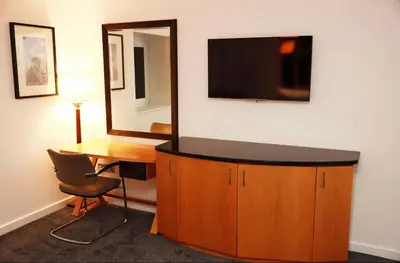 a room with a desk and a television on a wall at Maltings Hotel in Dunfermline