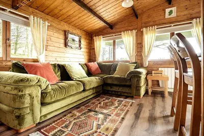 a living room with a green couch in a cabin at Torr Lodge- luxury log cabin with private hot tub! in Ballycastle