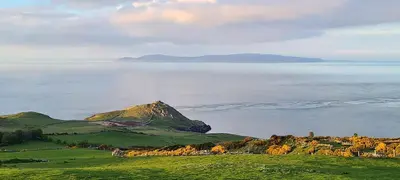 a view of a mountain in the middle of the ocean at Torr Lodge- luxury log cabin with private hot tub! in Ballycastle