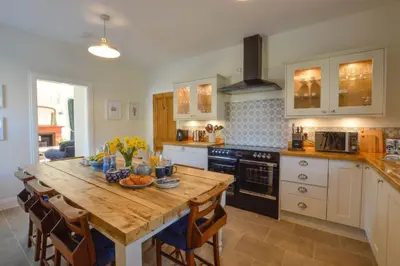 a kitchen with a wooden table with chairs and a tableablish at Achalic Farm House in Lerags