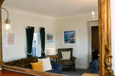 a mirror in a living room with a couch and a chair at Achalic Farm House in Lerags