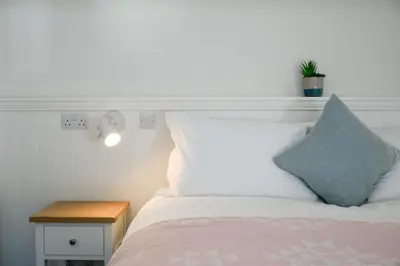 a bed with a white headboard and a blue pillow at Achalic Farm House in Lerags