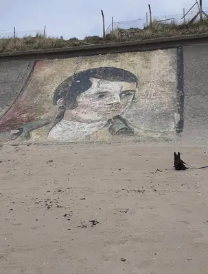 a cat sitting in front of a wall with a mural at Seaside Home in Ardeer Square