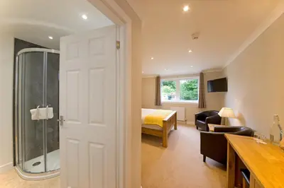 a bathroom with a shower and a bedroom at Falls of Lora Hotel in Oban
