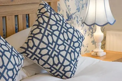 a bed with blue and white pillows and a lamp at Falls of Lora Hotel in Oban