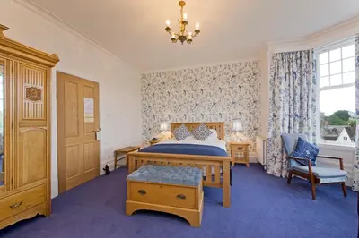 a bedroom with a bed and a chair and a chandelier at Falls of Lora Hotel in Oban