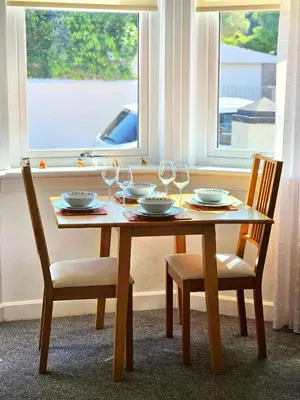 a wooden table with two chairs and wine glasses at Parkside 2 bedrooms appartment with encolsed garden in Largs